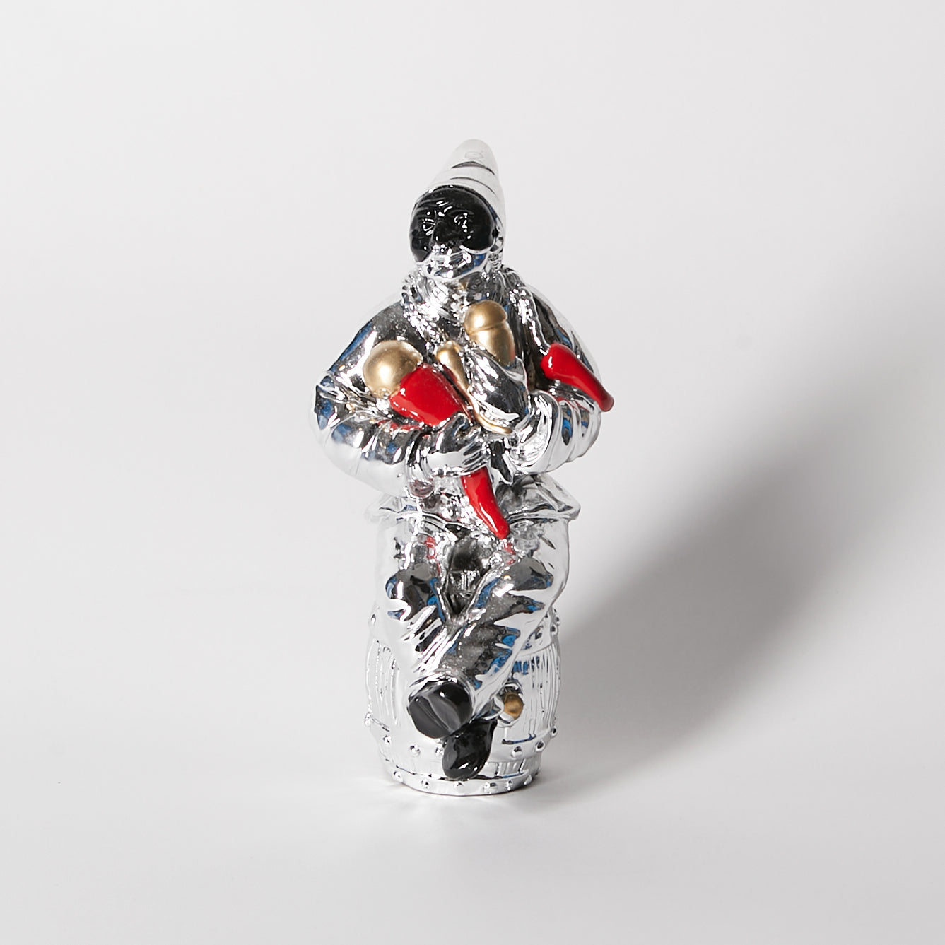 SILVER PULCINELLA WITH HORNS SITTING ON A BARREL